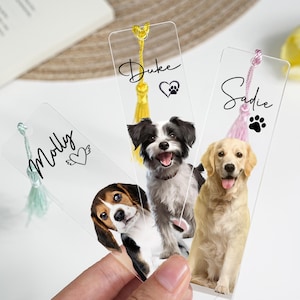 Puede incluir: Marcapáginas transparentes de acrílico con retratos de perros. Cada marcapáginas tiene una borla y un nombre: Molly, Duke y Sadie. El marcapáginas Duke tiene un corazón y una huella de pata, Sadie tiene una huella de pata y Molly tiene un corazón con alas.