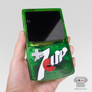 以下が含まれることがあります： 半透明の緑色のプラスチックシェルを備えた携帯型ゲーム機で、前面に7Upのロゴグラフィックが施されています。このデバイスには、黒い画面、ライトグレーの方向パッド、2つの白いAボタンとBボタン、および赤いセレクトボタンとスタートボタンが含まれています。