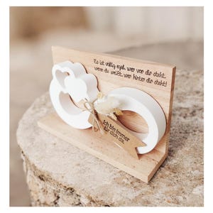 Könnte beinhalten: Ein dekoratives Holzstück mit einem weißen Herz- und Ringdesign. Das Stück trägt den deutschen Text "Es ist völlig egal, wer vor dir steht. wenn du weißt, wer hinter dir steht!" und den Text "Ich bin immer für dich da."