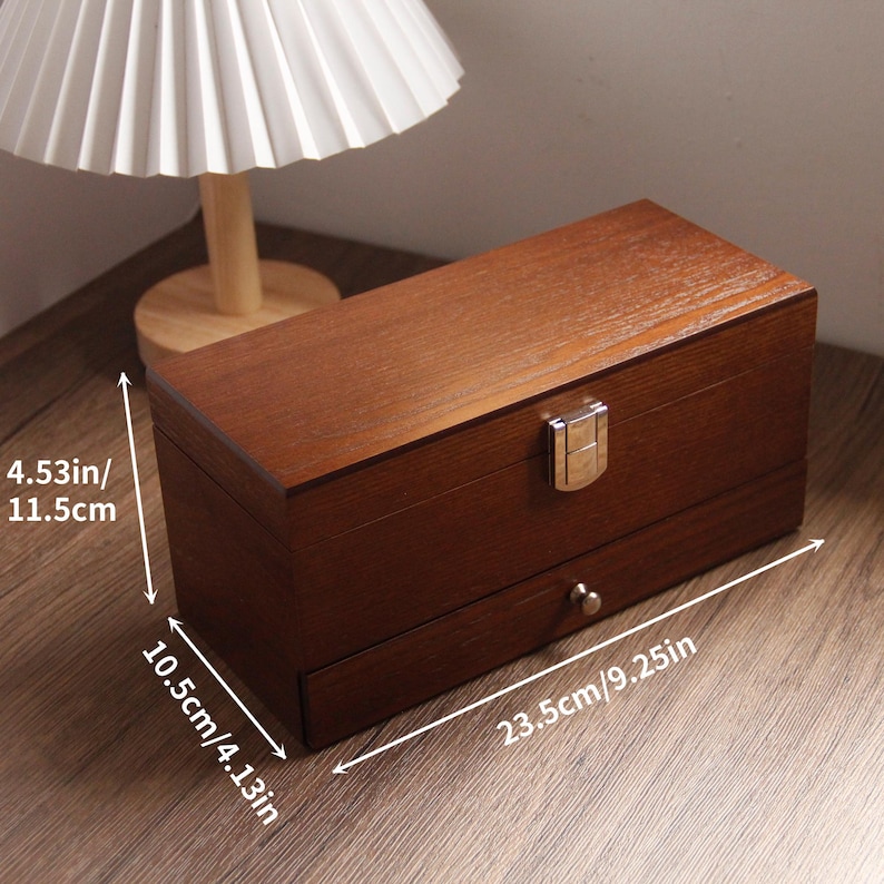 May include: A rectangular wooden box with a drawer, measuring 23.5 cm long, 10.5 cm wide, and 11.5 cm high. The box has a dark brown finish, a metal clasp, and a small drawer pull. The box is sitting on a wooden surface.