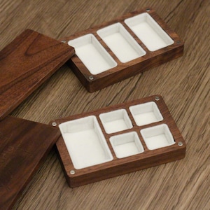 May include: Two wooden jewelry boxes with open lids. The boxes are rectangular with multiple compartments lined with white fabric. The wood has a rich, dark brown color. The boxes are on a wooden surface.
