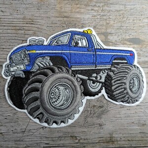 Pode incluir: Patch bordado com um monster truck azul com pneus cinzentos grandes. O camião tem uma faixa branca e detalhes amarelos. O patch é delineado em branco e foi concebido para ser passado a ferro ou cosido no tecido.