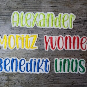 May include: Five embroidered name patches: "Alexander" in green, "Moritz" in yellow, "Yvonne" in red, "Benedikt" in blue, and "Linus" in green. Each name is stitched on a white felt background.