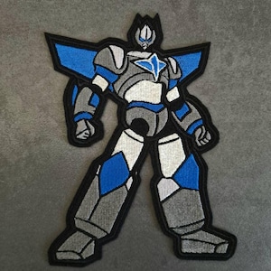 May include: Embroidered patch featuring a stylized robot in shades of gray, white, and blue, outlined in black. The robot has a star-shaped emblem on its chest and angular design elements, giving it a futuristic appearance. This patch is suitable for jackets, bags, or other fabric items.