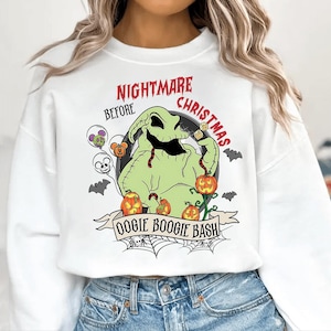 Op de afbeelding: Witte sweatshirt met een afbeelding van Oogie Boogie uit "The Nightmare Before Christmas". Het ontwerp bevat pompoenen, vleermuizen en de tekst "Nightmare Before Christmas" en "Oogie Boogie Bash".