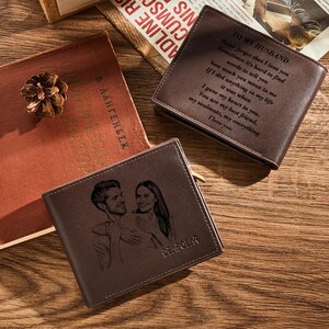 May include: Brown leather wallets with personalized engravings. One wallet features a couple's portrait, another has a loving message, and a third displays text. The wallets are displayed on a wooden surface.