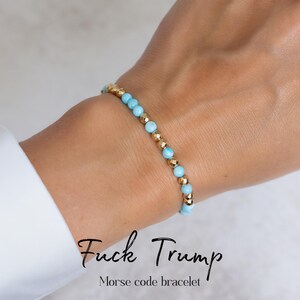 May include: A bracelet with light blue and gold beads. The text "Fuck Trump" and "Morse code bracelet" are displayed in black cursive font.