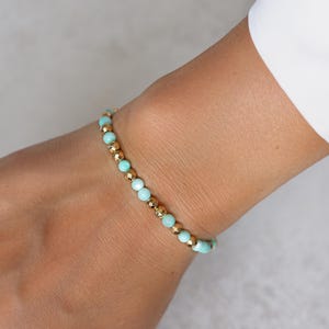 Puede incluir: Una delicada pulsera con cuentas alternas de color azul claro y dorado. La pulsera se lleva en la mu&ntilde;eca, mostrando el dise&ntilde;o y el contraste de color de la joya. Las cuentas doradas a&ntilde;aden un toque de elegancia a la pieza.
