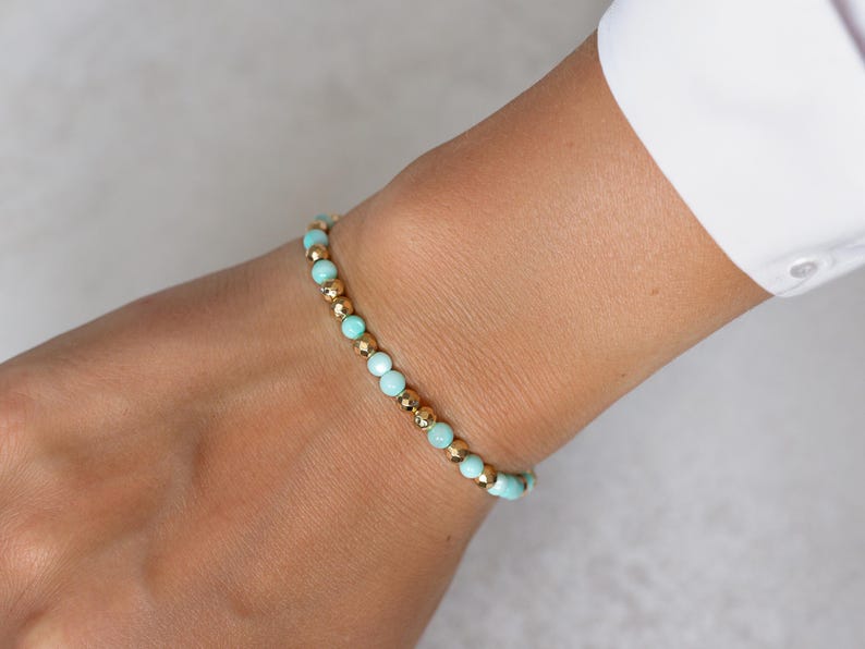 Puede incluir: Una delicada pulsera con cuentas alternas de color azul claro y dorado. La pulsera se lleva en la mu&ntilde;eca, mostrando el dise&ntilde;o y el contraste de color de la joya. Las cuentas doradas a&ntilde;aden un toque de elegancia a la pieza.
