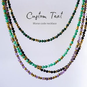 May include: Three layered beaded necklaces with green, black, and purple beads, accented with gold-colored spacers. The necklaces are displayed against a white background. Text in the image reads "Custom Text Morse code necklace."