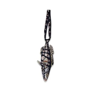 Peut inclure: Une cravate en forme de poisson avec un corps à motifs noirs, blancs et fauves. La cravate possède une longue sangle étroite sur le dessus pour l'attacher, et le corps du poisson présente des détails d'écailles et de nageoires réalistes.