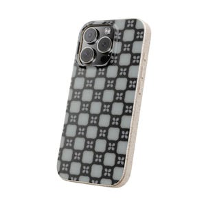 May include: A smartphone case with a geometric floral pattern in grey and black. The case has a light beige border and a camera module with three lenses. The design features a repeating pattern of square and flower shapes.