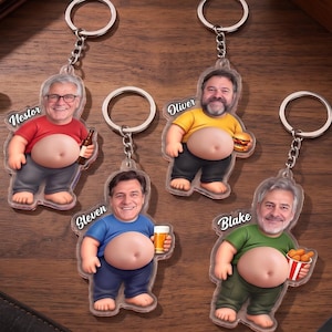 Puede incluir: Cuatro llaveros de acrílico con figuras estilo caricatura que muestran vientres expuestos y rostros de hombres. Cada figura viste una camiseta y pantalones de colores, sosteniendo objetos como una botella de cerveza, hamburguesa, vaso de cerveza o papas fritas. Los nombres Nestor, Oliver, Steven y Blake están impresos.
