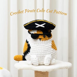 May include: A crocheted calico cat wearing a pirate hat and eye patch. The cat is white, orange, and black, and the hat is black and gold with a white cross. The text "Crochet Pirate Calico Cat Pattern" is above the cat.