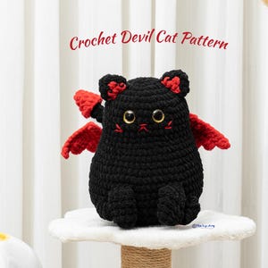 Puede incluir: Un gato negro de ganchillo con alas y detalles rojos. El gato tiene ojos grandes y redondos y una pequeña cara bordada. El texto "Crochet Devil Cat Pattern" se muestra encima del gato.