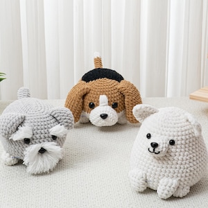 May include: Three handmade crochet dog toys. A gray Schnauzer with a white beard, a brown and white Beagle, and a white dog with black eyes and nose. The toys are on a white surface.