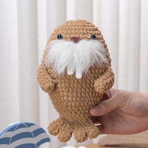 May include: A white ceramic mug with a black handle and the text "But First, Coffee" in a black, handwritten-style font. The mug is on a white surface.