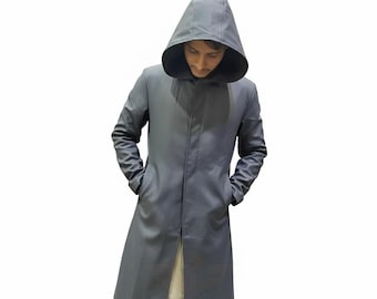 May include: A long, gray hooded coat with a button closure and pockets. The coat is made of a smooth material and has a tailored fit. The hood is large and covers the head. The person is wearing a light-colored shirt and khaki pants.