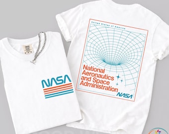 May include: Two white t-shirts with NASA logos. One shirt has the NASA logo on the front, and the other has a graphic of a wormhole and the words "National Aeronautics and Space Administration" on the back.