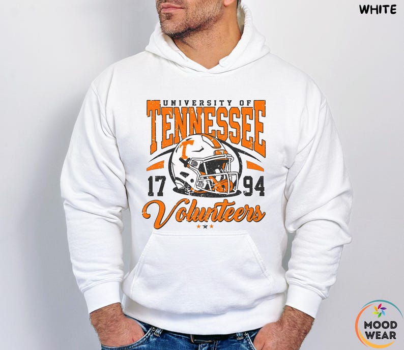 May include: White hoodie featuring the University of Tennessee Volunteers logo in orange and white. The design includes a football helmet, the years 17 and 94, and the word "Volunteers". The hoodie has a front pocket and a drawstring hood.