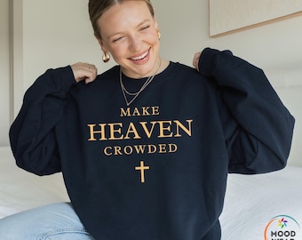 May include: A navy blue crew neck sweatshirt featuring the gold text "MAKE HEAVEN CROWDED" and a gold cross. The sweatshirt is a comfortable style, suitable for casual wear.