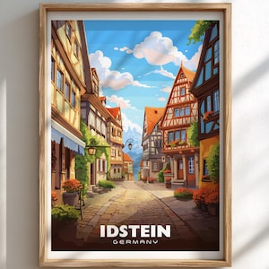 May include: A framed print showing a vibrant illustration of Idstein, Germany. The image portrays a cobbled street flanked by traditional half-timbered buildings, set against a blue sky with clouds. The town's name is written in white text.