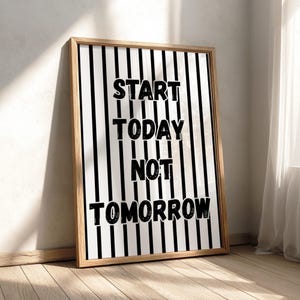 May include: A rectangular framed wall art piece featuring a white background with vertical black stripes. The text "START TODAY NOT TOMORROW" is printed in bold, black, distressed-style capital letters centered across the striped pattern.