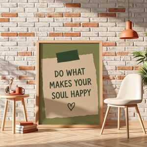 Pu&ograve; includere: Un quadro rettangolare con un ritaglio di carta color sabbia su sfondo verde oliva. Il testo "DO WHAT MAKES YOUR SOUL HAPPY" &egrave; scritto in lettere maiuscole verde scuro, con un piccolo cuore disegnato a mano e un pezzo di nastro adesivo.