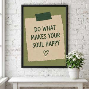 Pu&ograve; includere: Una stampa incorniciata che mostra un foglietto di carta beige dai bordi strappati fissato con un pezzo di nastro adesivo verde scuro su uno sfondo verde oliva. Il testo DO WHAT MAKES YOUR SOUL HAPPY &egrave; scritto in verde scuro sopra un cuore.