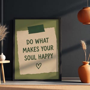 Pu&ograve; includere: Una stampa artistica incorniciata con un ritaglio di carta beige su sfondo verde oliva. Il testo DO WHAT MAKES YOUR SOUL HAPPY &egrave; scritto in lettere maiuscole verde scuro, con un piccolo cuore disegnato a mano sotto il testo.