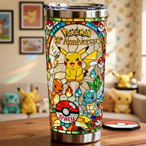 May include: Stainless steel tumbler with a stained glass design featuring Pikachu and other Pokémon characters. The tumbler is decorated with the text "Pokémon 30th Anniversary" and the name "Tracy".