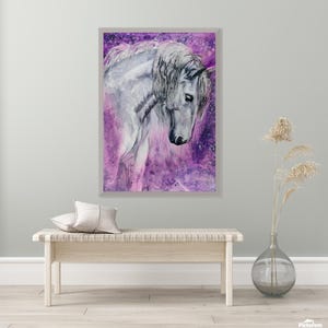 Op de afbeelding: Waterverfschilderij van een wit paard met een vloeiende manen en een serene uitdrukking. Het paard staat tegen een levendige paarse en roze achtergrond, omlijst door een lichtgrijze rand. Het kunstwerk roept een gevoel van gratie en rust op.