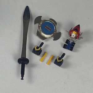 May include: A collection of toy accessories, including a black sword, a silver and blue circular weapon, a red and silver vehicle, two pairs of black and yellow arm pieces, and two yellow rods. The items are arranged on a white surface.