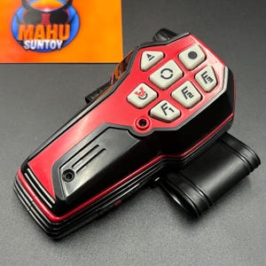 May include: A red and black toy walkie-talkie with several white buttons and a black belt clip. The walkie-talkie has the text "MAHU SUNTOY" on a yellow and blue background.