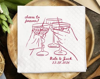 Op de afbeelding: Witte cocktailservetten met een rode illustratie van drie glazen die klinken, elk met een kers. De tekst "cheers to forever!" en de namen "Kate & Jack" met de datum "12.28.2025" zijn rood gedrukt.
