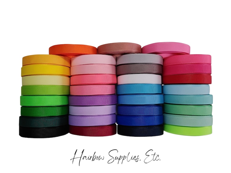 May include: A collection of 18 spools of colorful ribbon, arranged in a rainbow pattern. The ribbon is a solid color and has a satin finish. The spools are stacked on top of each other, with the colors transitioning from red to purple to blue to green to yellow to orange. The text "Hairbow Supplies. Etc." is printed on a white background below the ribbon.