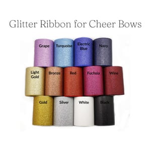 May include: A collection of glitter ribbon rolls in various colors, including grape, turquoise, electric blue, and navy. The image also shows light gold, bronze, red, fuchsia, wine, gold, silver, white, and black rolls. Text reads "Glitter Ribbon for Cheer Bows."