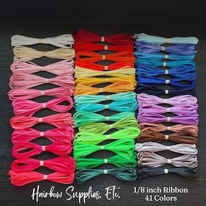 May include: An assortment of 41 colors of 1/8 inch ribbon, neatly bundled and secured with rubber bands. The ribbons span a wide spectrum of hues, from pastels to vibrant shades, including pinks, blues, greens, and reds. Text reads "Hairbow Supplies, Etc."