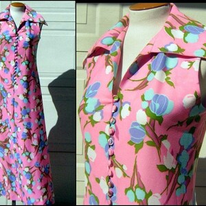 K&ouml;nnte beinhalten: Ein &auml;rmelloses Maxikleid mit rosa Hintergrund und einem Blumenmuster in Blaut&ouml;nen, Wei&szlig; und Gr&uuml;n. Das Kleid hat einen gro&szlig;en Kragen und eine Knopfleiste vorne.
