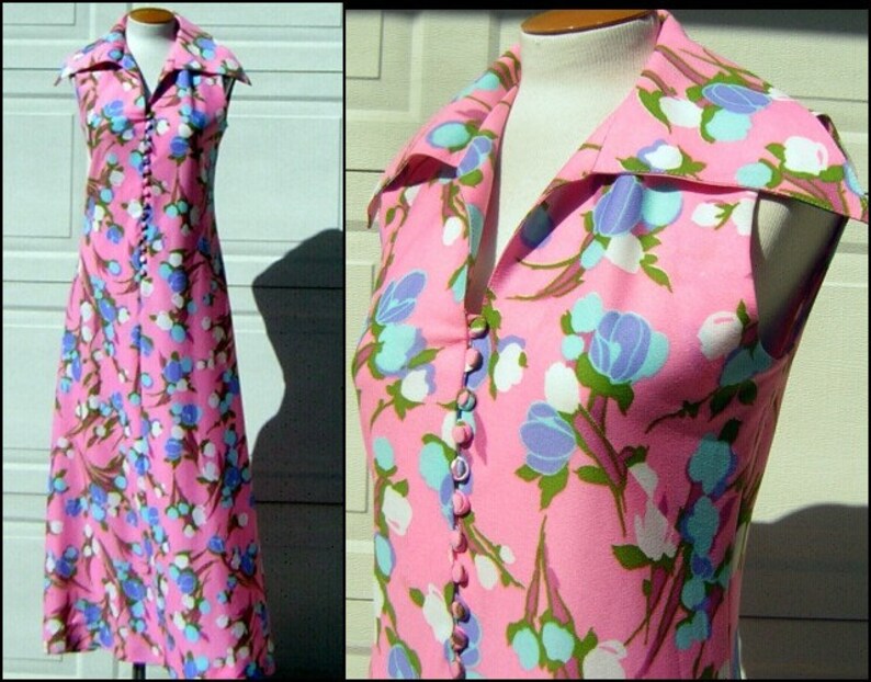 K&ouml;nnte beinhalten: Ein &auml;rmelloses Maxikleid mit rosa Hintergrund und einem Blumenmuster in Blaut&ouml;nen, Wei&szlig; und Gr&uuml;n. Das Kleid hat einen gro&szlig;en Kragen und eine Knopfleiste vorne.