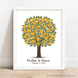 May include: A white frame with a white mat surrounding a print of a stylized orange tree with green leaves and yellow oranges. The oranges are filled with black handwriting. The tree trunk is brown and the text "Colin & Sara October 5, 2013" is below the tree.