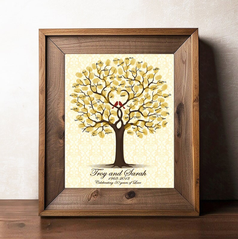 Peut inclure: Une impression encadr&eacute;e d'un arbre aux feuilles dor&eacute;es et deux oiseaux rouges perch&eacute;s sur une branche en forme de c&oelig;ur. L'arbre est entour&eacute; d'un fond blanc avec un motif d&eacute;licat. Le texte "Troy and Sarah 1963-2013 Celebrating 50 years of Love" est imprim&eacute; sous l'arbre.