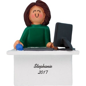 May include: A personalized Christmas ornament featuring a woman with brown hair sitting at a white desk with a computer and a blue mouse. The desk has a white sign with the text "Stephanie 2017".