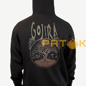 May include: Black hoodie featuring the band name "GOJIRA" arched across the upper back. Below, a circular design depicts a tree with roots, branches, and symbols. The design is in shades of brown and tan.