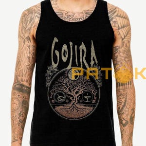 May include: Black tank top featuring the band name "Gojira" in a stylized font above a circular graphic. The graphic depicts a tree with roots, a snake, and a chalice. The design is in shades of brown and tan.