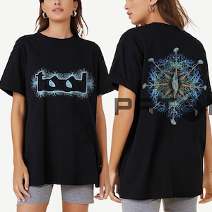 May include: Black t-shirt with the band name "Tool" in a light blue and black design on the front. The back of the shirt features a detailed, colourful graphic with a central design and radiating elements.