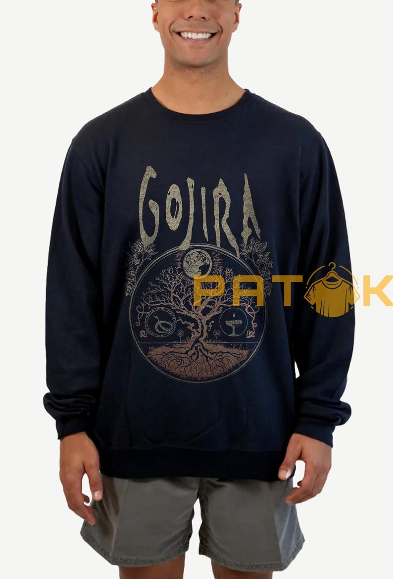 May include: Navy blue sweatshirt featuring the band name "GOJIRA" in a distressed gold font. The front graphic includes a circular design with a tree, moon, and other symbols. The sweatshirt is long-sleeved.