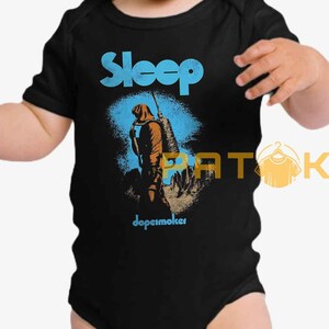 Pu&ograve; includere: Body da bambino nero con grafica blu e arancione. La parola "Sleep" &egrave; in blu sopra un'illustrazione di una figura con uno zaino. Il testo "dopesmoker" &egrave; sotto l'illustrazione.