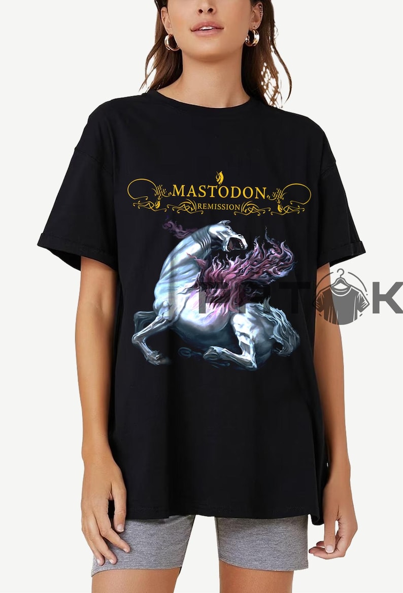 May include: Black t-shirt featuring the band name "Mastodon" in gold script above a graphic of a rearing, mythical creature with a flowing mane. The word "Remission" is below the band name.