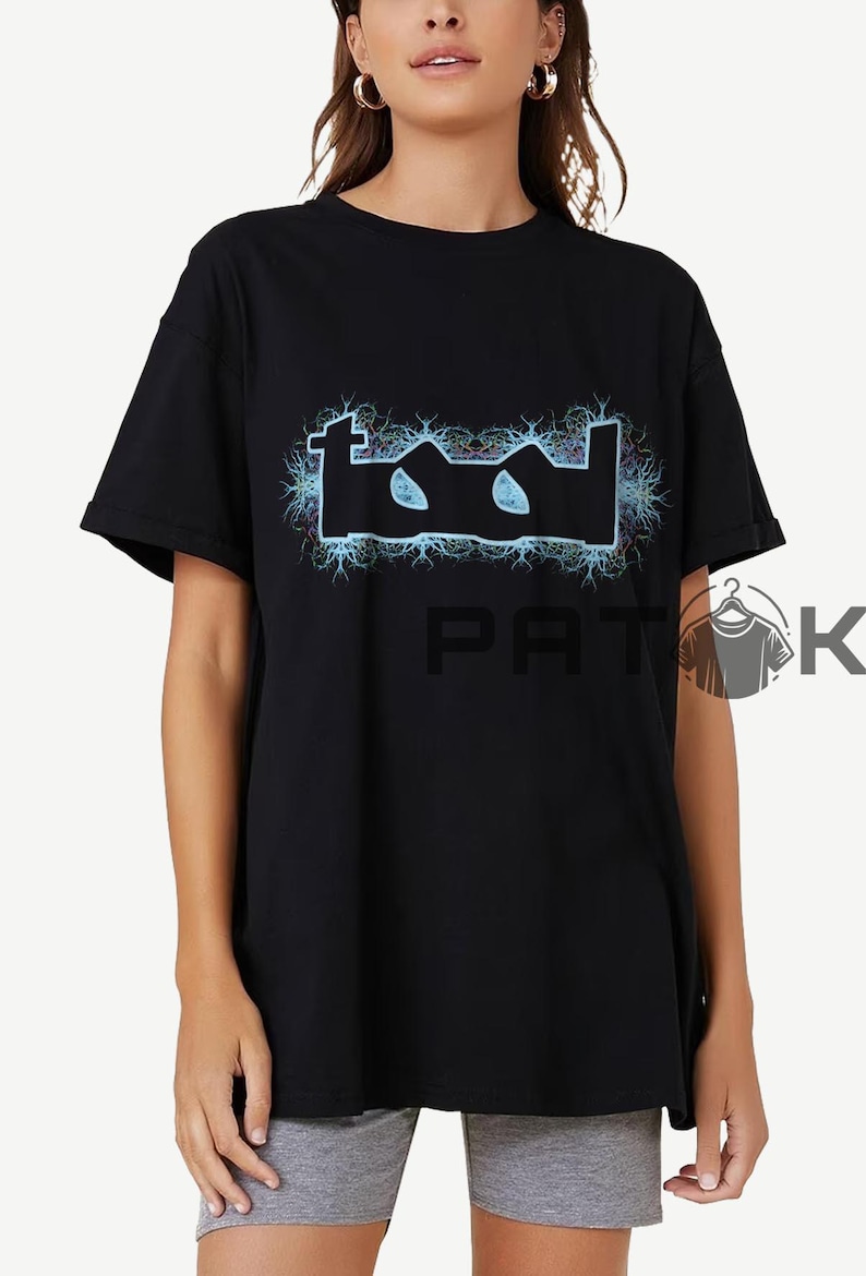 May include: Black t-shirt with the band name "TOOL" in a stylized, electric blue design. The logo is surrounded by a blue and white lightning bolt pattern. The shirt has a classic crew neck.